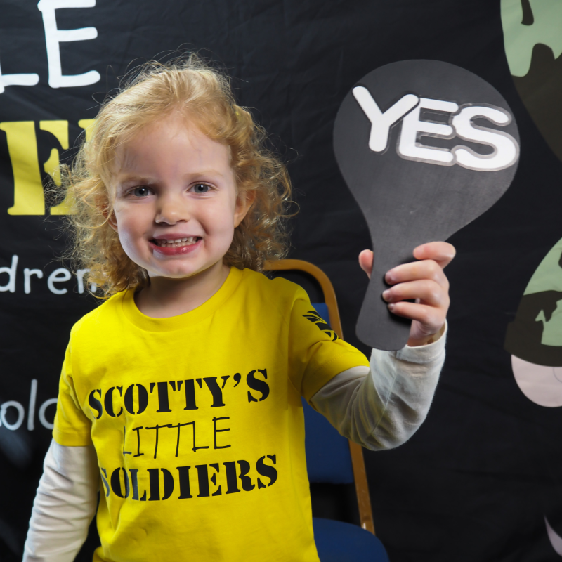 Scotty's Member in yellow Scotty's t-shirt at the Christmas Party holding up YES sign