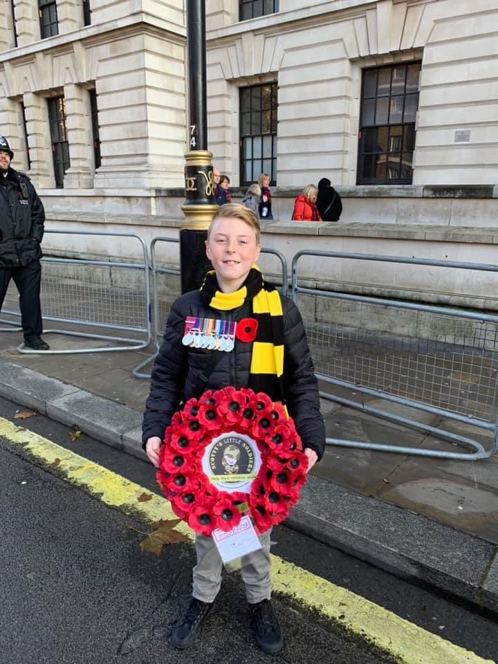 Army child Ben at the Remembrance Day Parade in London in 2019 holding a Scotty's Little Soldiers' wreath of poppies