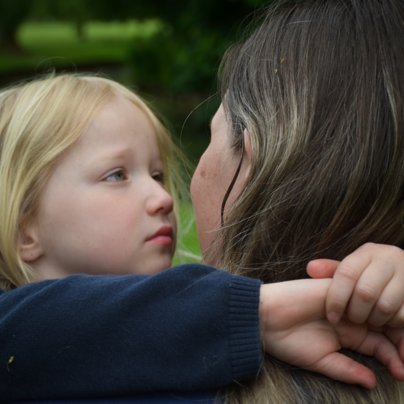 Parent supporting a bereaved military child who has experienced the death of a parent in the British Armed Forces. Blonde girl looks into the eyes of mother with arms around her