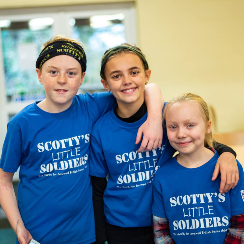 Bereaved British Forces young people at Scotty's Little Soldiers London Event in blue t-shirts with arms around each other
