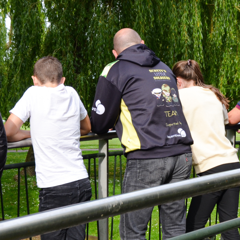 Scotty's Little Soldiers child and young person support worker with two bereaved military children on bridge in a park
